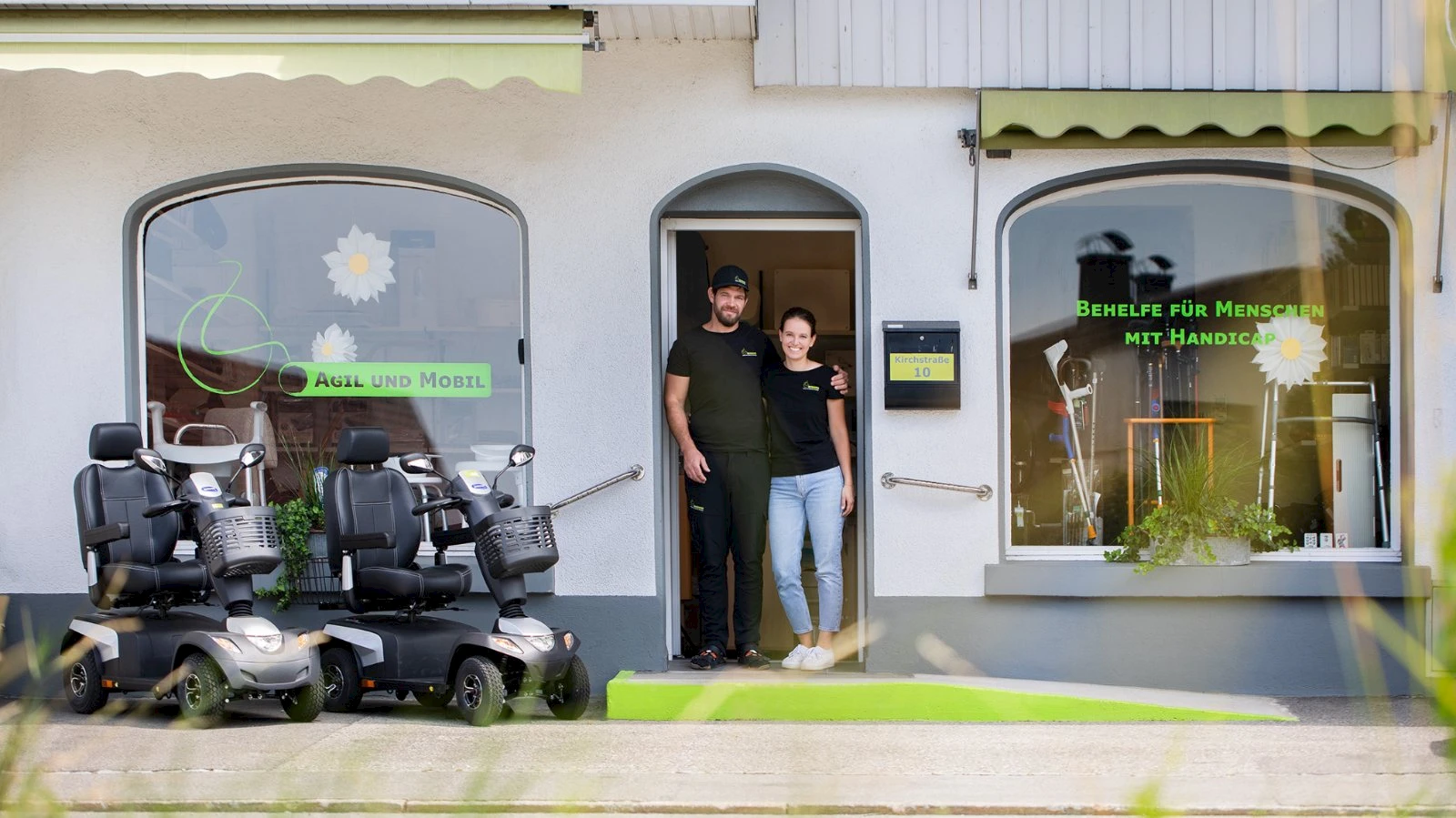 Franz-Josef und Melissa Feurstein stehen in der Tür ihres Geschäfts in der Kirchstraße 10 in Lustenau, davor zwei Elektromobile